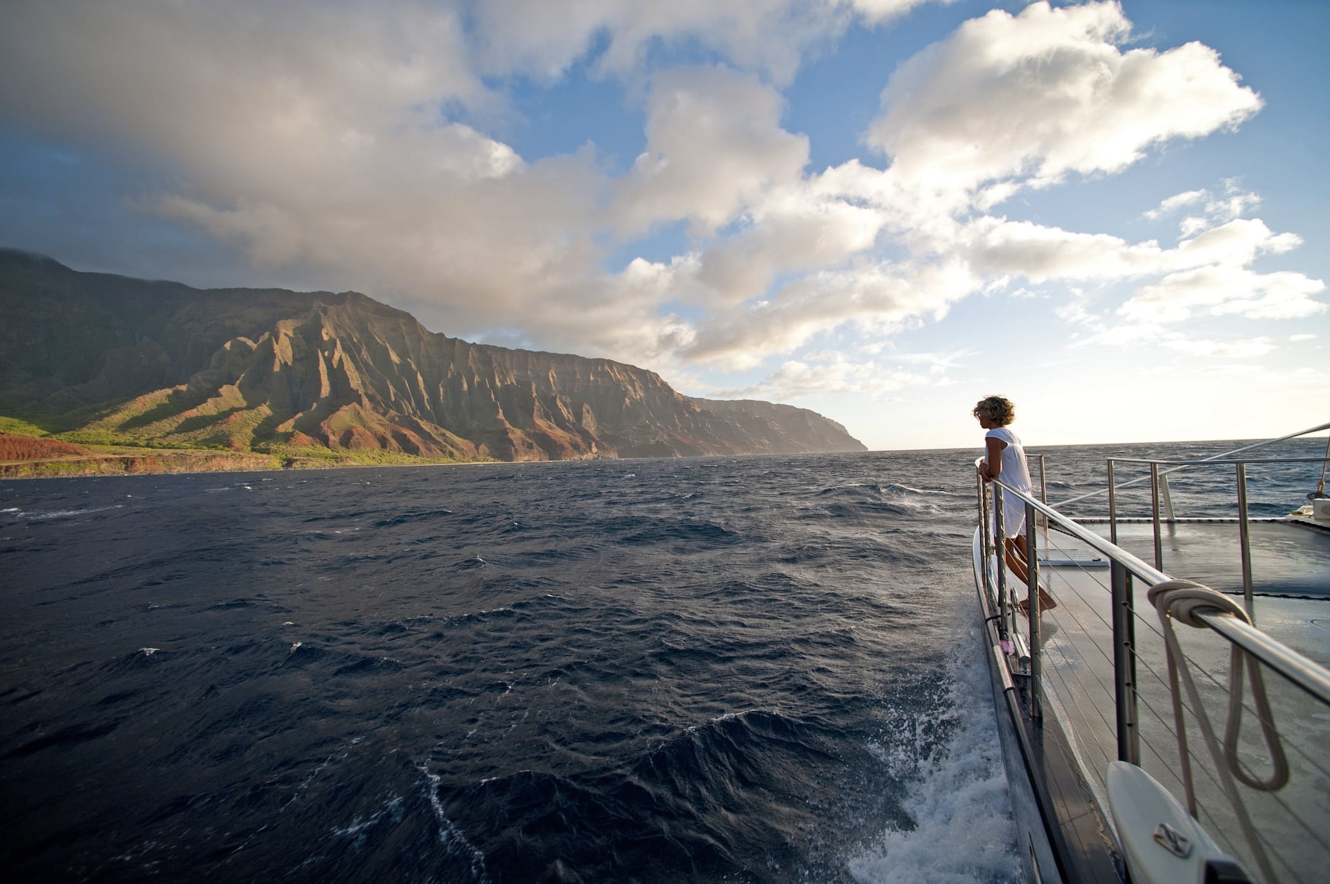 Woman admiring Napali Coast at sunset on a Kauai sailboat charter