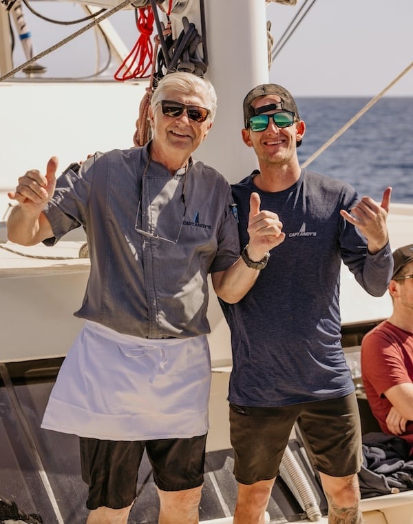 Two crew members from Captain Andy's smile and pose with shaka signs.