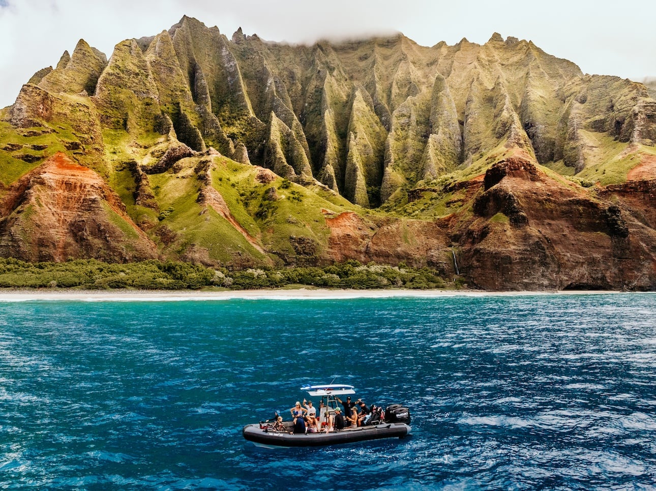 A private boat tour Kauai raft expedition with people having a great time and Napali in the background.