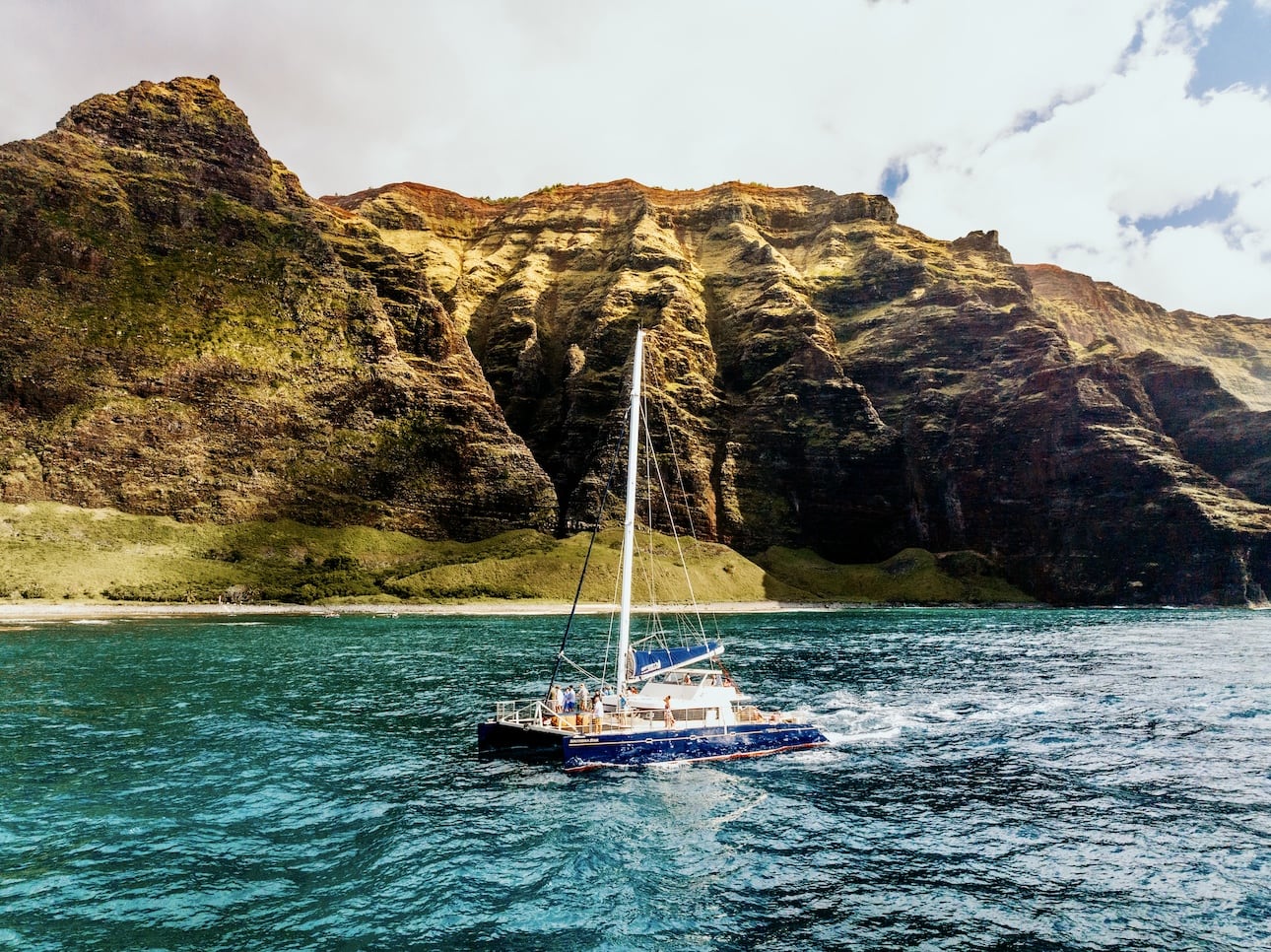 Captain Andy's sailing catamaran Kauai Na Pali Coast, with towering cliffs in the background and clear blue ocean water.