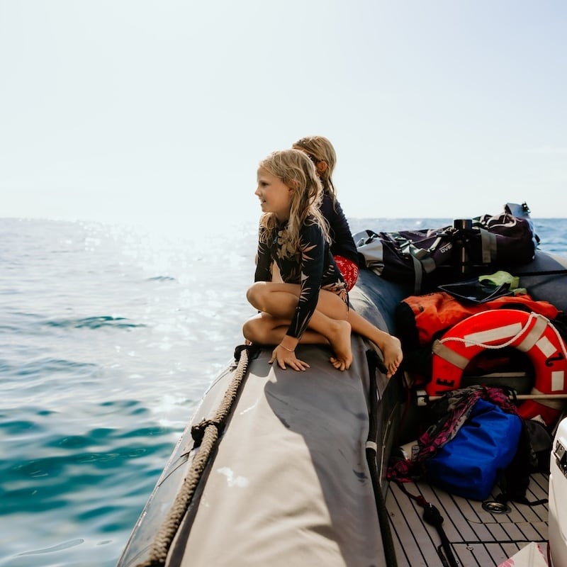 Kids sitting on the side of a zodiac on a snorkel boat tour Kauai.