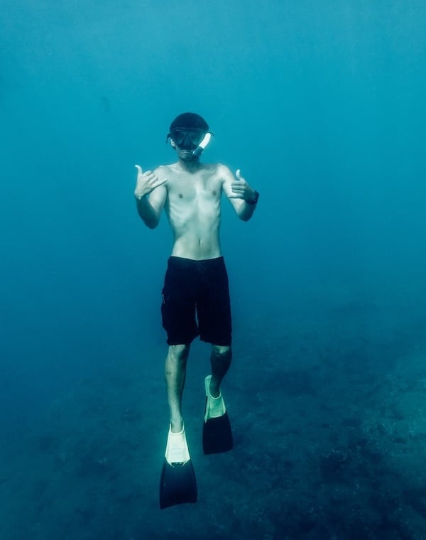 Man underwater giving double shaka on the best snorkeling tour in Kauai.