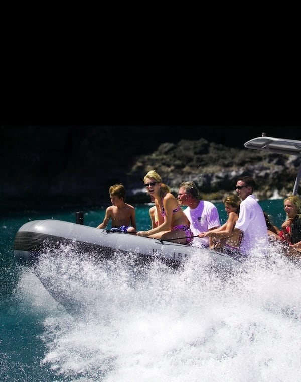 Group of people enjoying a thrilling ride on a speedboat, with water splashing around them.