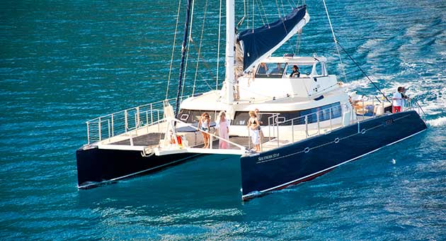 Napali Coast tours catamaran in blue Pacific waters.